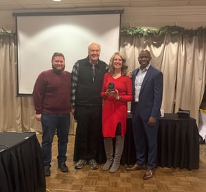 Michelle Bostinelos pictures with Josh Bush, Jon Winkel, and Brian Pearson accepting award for 20 years of service